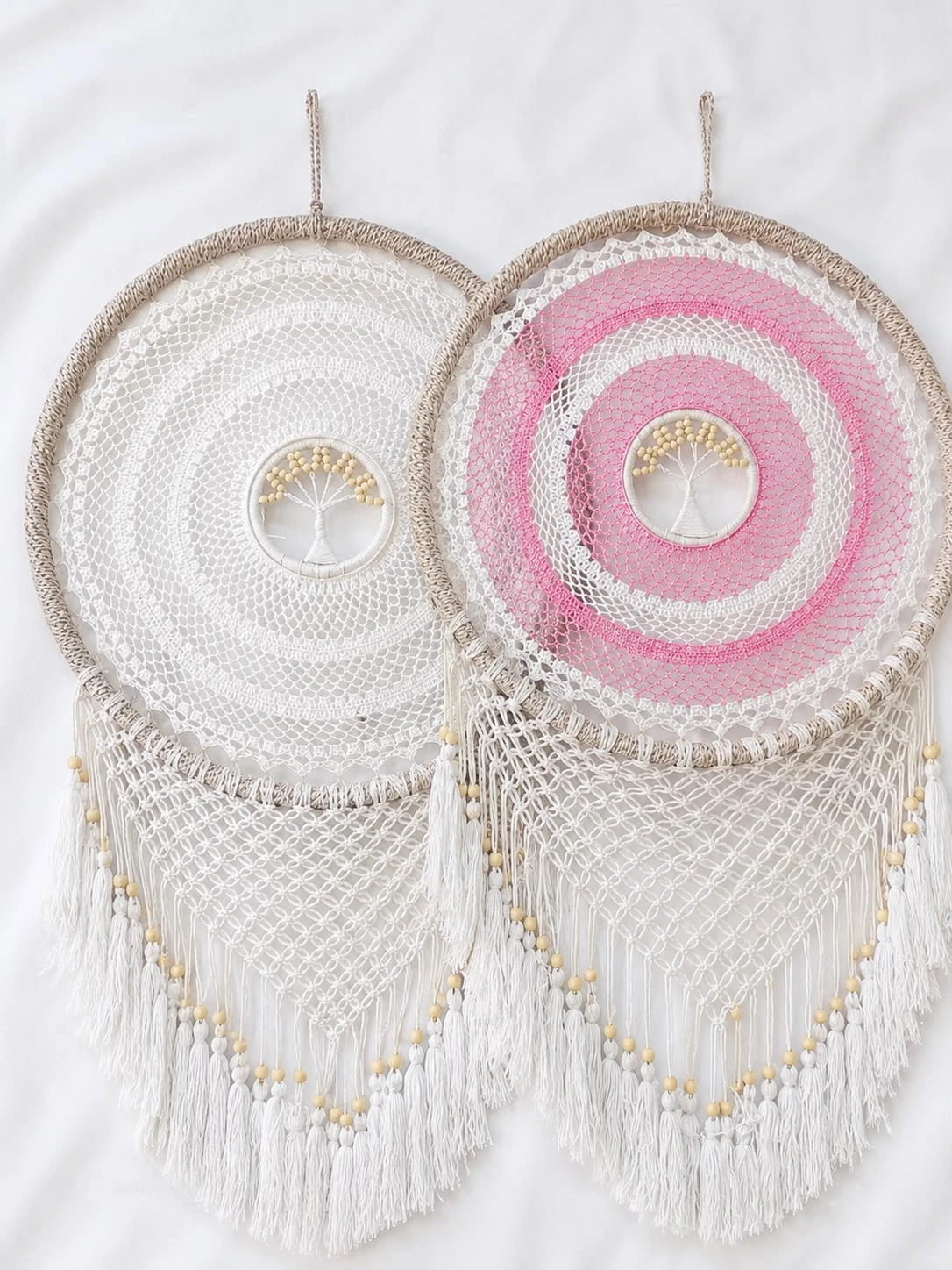 Set of two round macramé tree of life wall hangings with bead tree centre and long tasseled fringe, in white and pink